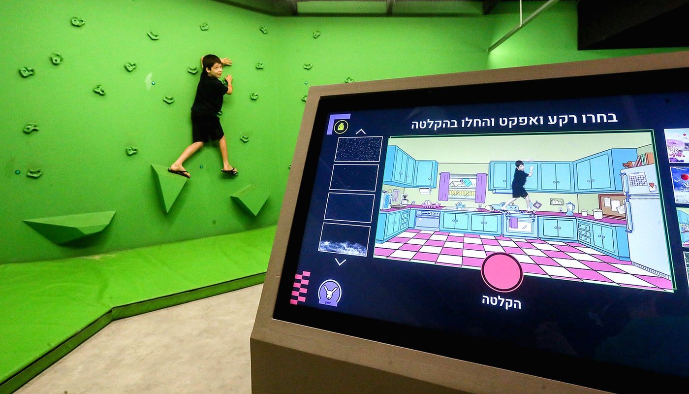 ילד מטפס על קיר הטיפוס הירוק